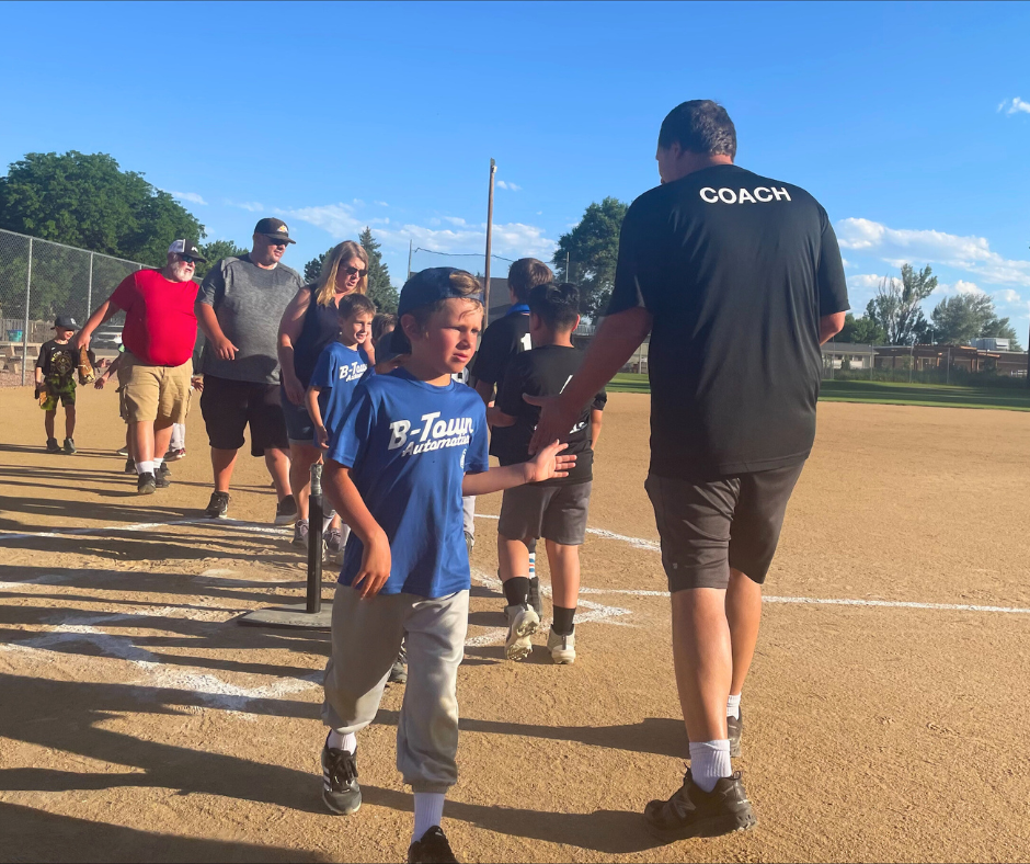 Photo of a baseball coach shaking hands with t-ball players post-game