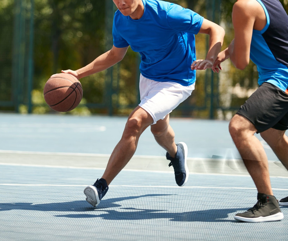 Two people playing basketball on an outdoor court
